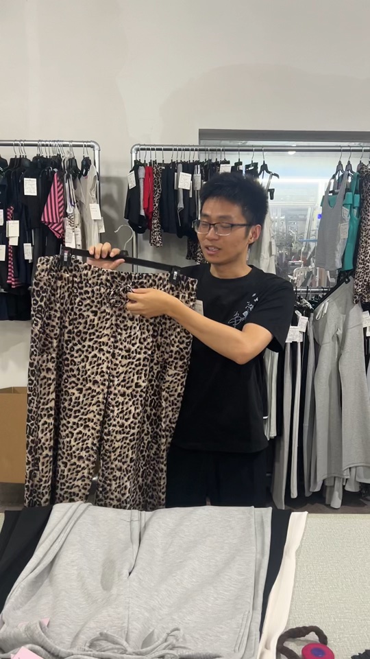 HF Garments presenter holding leopard-print pants while explaining questions to ask an activewear manufacturer