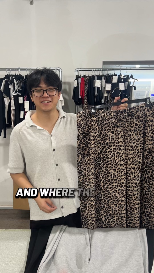 HF Garments presenter holding leopard-print pants during a sample review discussion